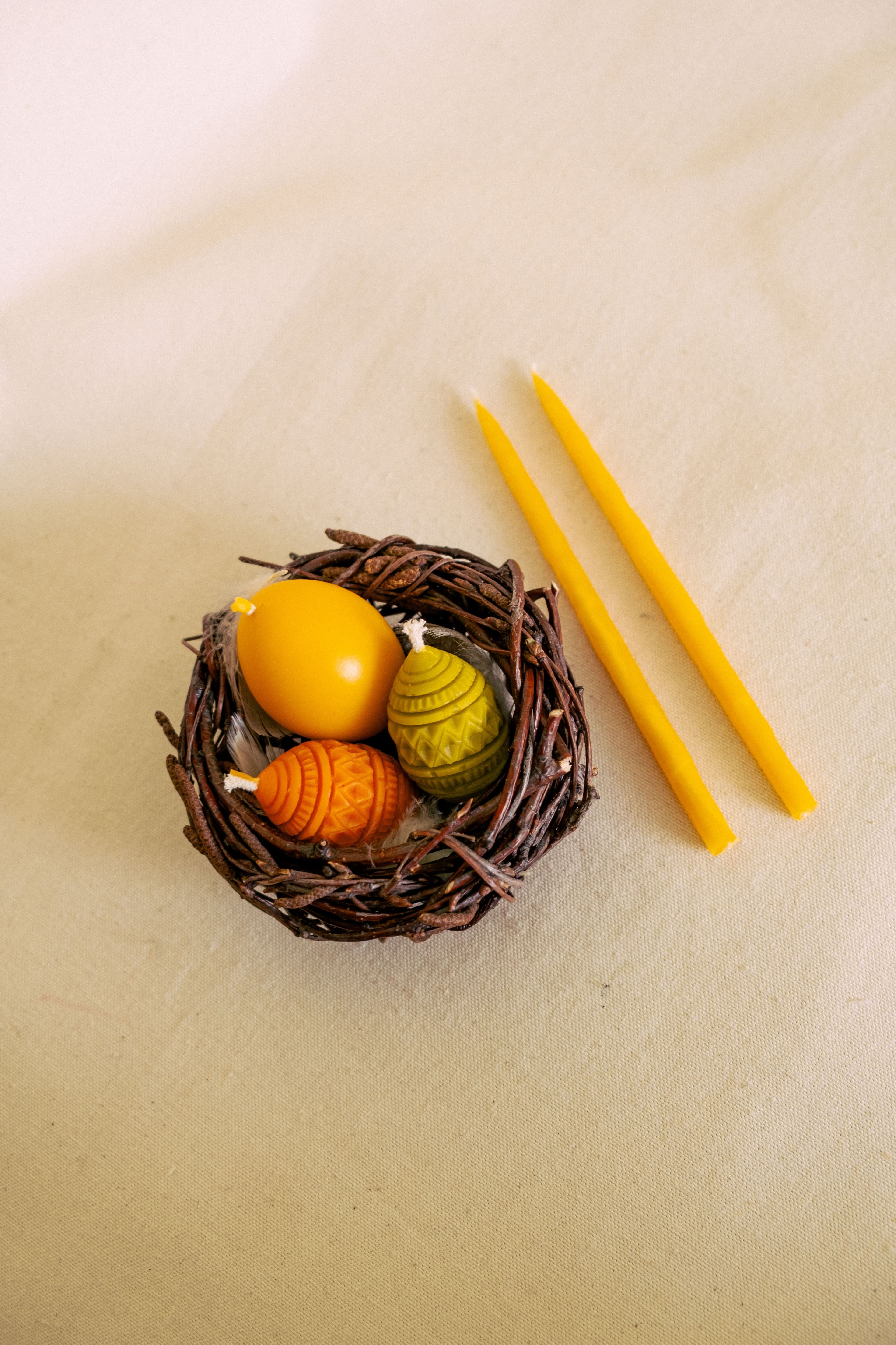 Набір яєчок в корзинці з березових гілочок та дві свічечки